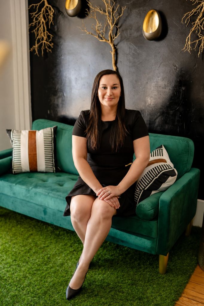 Bre Meador, Bastrop County REALTOR®, seated on a green velvet sofa in a styled living room